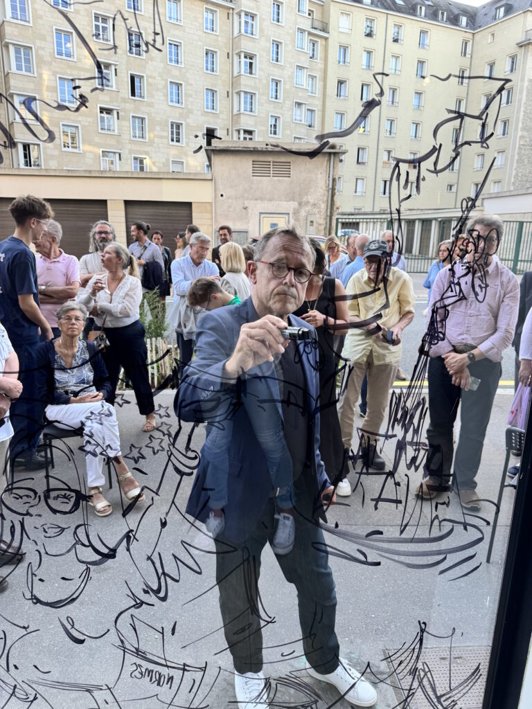Artiste dessinant sur une vitre devant des visiteurs