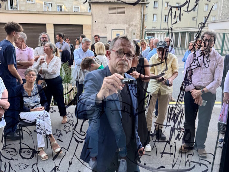 Emmanuel Chaunu dessinant sur une vitre devant des spectateurs